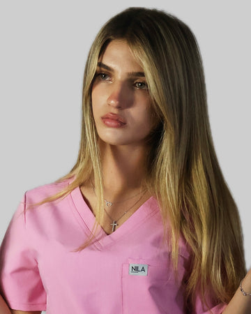 Woman wearing blush pink Nila scrubs in a professional medical setting