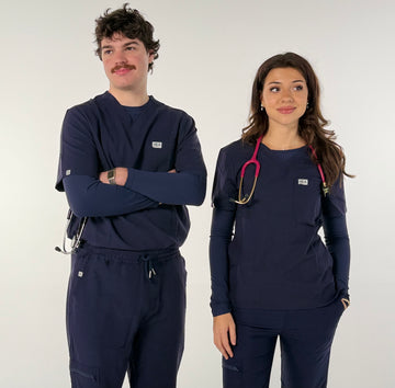 Two individuals wearing navy blue medical scrubs with stethoscopes on a white background